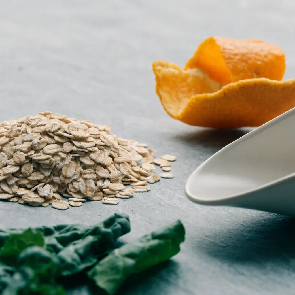 Whole-food vitamin D3 sources arranged on a matte grey stone surface with a small ceramic scoop